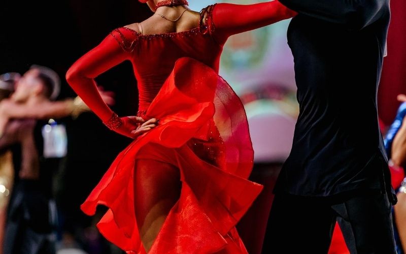 Woman in red dress and her male partner dancing in competition.