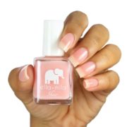 Pink nail polish being held in hand.